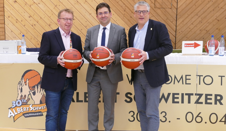 Bürgermeister Matthias Baaß, Regierungspräsident Jan Hilligardt und DBB-Funktionär Stefan Raid mit Basketbällen in der Hand auf dem Spielfeld in der Sporthalle.